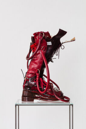 Puzzlecut Boot Oxblood, 2021. Recycled shoes, handbags and belts, shoe last, glue, thread, steel, glass. Courtesy the artist and Soft Opening, London. Photo: Kunst Dokumentation