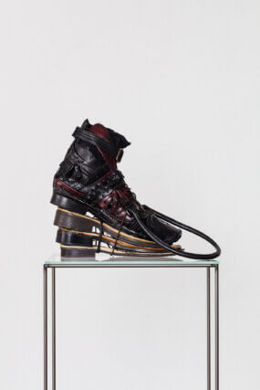 Puzzlecut Boot Black, 2021. Recycled shoes, handbags and belts, shoe last, glue, thread, steel, glass. Courtesy the artist and Soft Opening, London. Photo: Kunst Dokumentation